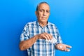 Senior hispanic man holding pills relaxed with serious expression on face