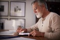 Senior Hispanic man sitting at a table using a tablet computer  in the evening, close up, side view Royalty Free Stock Photo