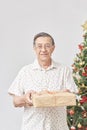 Senior Hispanic man smiling as he hands over a Christmas gift to the camera Royalty Free Stock Photo