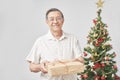 Senior Hispanic man smiling as he hands over a Christmas gift to the camera Royalty Free Stock Photo