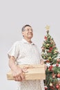 Senior Hispanic man smiling as he hands over a Christmas gift to the camera Royalty Free Stock Photo