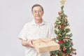 Senior Hispanic man smiling as he hands over a Christmas gift to the camera Royalty Free Stock Photo