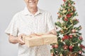 Senior Hispanic man smiling as he hands over a Christmas gift to the camera Royalty Free Stock Photo