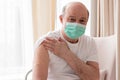 Senior hispanic man wearing face mask showing vaccinated arm.