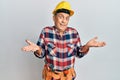 Senior hispanic man wearing handyman uniform clueless and confused expression with arms and hands raised Royalty Free Stock Photo