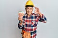 Senior hispanic man wearing handyman uniform and hardhat doing ok sign with fingers, smiling friendly gesturing excellent symbol Royalty Free Stock Photo