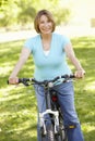 Senior Hispanic Woman Cycling In Park Royalty Free Stock Photo