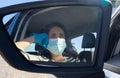 Senior Hispanic woman with face mask and latex gloves driving her car viewed from the rear view mirror of the car Royalty Free Stock Photo