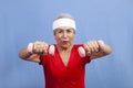 Senior hispanic woman in a sweatband lifting weights