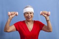 Senior hispanic woman in a sweatband lifting weights