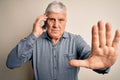 Senior hoary man having conversation talking on the smartphone over white background with open hand doing stop sign with serious