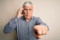 Senior hoary man having conversation talking on the smartphone over white background pointing with finger to the camera and to