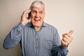 Senior hoary man having conversation talking on the smartphone over white background pointing and showing with thumb up to the