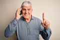 Senior hoary man having conversation talking on the smartphone over white background surprised with an idea or question pointing