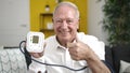 senior holding tensiometer with thumb up at home