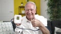 senior holding tensiometer with thumb up at home