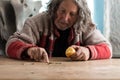 Senior homeless man eating an apple counting coins Royalty Free Stock Photo