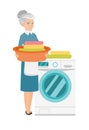 Senior housewife using washing machine at laundry.