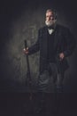 Senior hunter with a shotgun in a traditional shooting clothing, posing on a dark background. Royalty Free Stock Photo