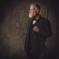 Senior hunter with a shotgun in a traditional shooting clothing, posing on a dark background Royalty Free Stock Photo