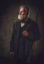 Senior hunter with a shotgun in a traditional shooting clothing, posing on a dark background Royalty Free Stock Photo