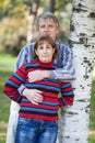 Senior husband embracing her wife while standing near birch tree in park Royalty Free Stock Photo