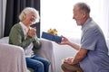 senior husband making surprise giving gift box to pretty wife, happy aged woman get unexpected present