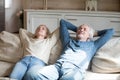Senior husband and wife relaxing on couch with eyes closed