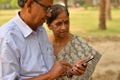 Senior Indian Bengali couple in park looking at their smart phone and smiling in a park in New Delhi, India. Concept love Royalty Free Stock Photo