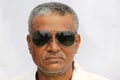 Senior Indian man cropped portrait view wearing sun glass and serious look closeup on white background.