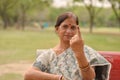 Senior Indian woman sitting on the red bench in a park and showing their inked finger after casting their vote in Indian assembly Royalty Free Stock Photo