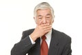 Senior Japanese businessman making the speak no evil gesture