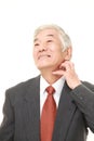 Senior Japanese businessman scratching his neck