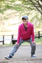 Senior Japanese man wearing pink parka doing leg stretch outdoor