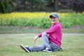 Senior Japanese man wearing pink parka doing seated torso twist stretch on a lawn Royalty Free Stock Photo