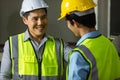 Senior and junior engineers talking together with intimated manner beside the machine in factory. Concept for good teamwork and