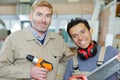 Senior and junior workmen in workshop holding drill and saw Royalty Free Stock Photo