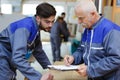 Senior laborer in blue work wear with colleague