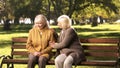 Senior lady comforting old friend about her loss, sitting on bench in park