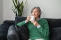 Senior lady daydreaming and enjoying a hot drink