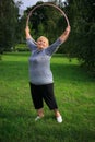Senior lady doing gymnastic with hula-hoop in the park Royalty Free Stock Photo