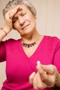 Senior lady with headache holding tablet or pill Royalty Free Stock Photo