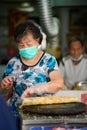 Senior lady in a mask preparing pancake in Tai O, Hong Kong