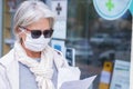 Senior lady with mask and protective gloves leaves the pharmacy with medicines and instructions. Fear of coronavirus infection,