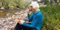 Senior lady resting and eating chocolate brownie following a long walk Royalty Free Stock Photo