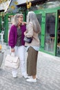 Senior lady talks to silver haired friend meeting on modern city street