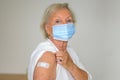 Senior lady wearing a face mask showing her arm to prove she has been vaccinated