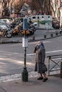 Senior lady wearing a surgery mask, checking the timetable at a bus stop in Marseille, France