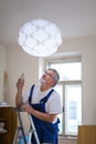 Senior landlord hanging a new light in a rental appartement Royalty Free Stock Photo