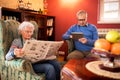 Senior lovely couple relax at home while reading newspaper and u Royalty Free Stock Photo